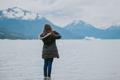 Rear view of woman on snowcapped mountain against sky