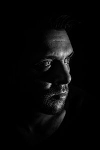 Close-up of thoughtful mid adult man looking away against black background