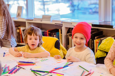 Portrait of happy friends sitting on table