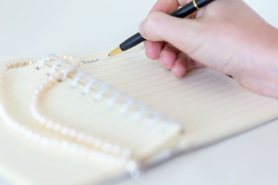 Cropped hand writing in book at home