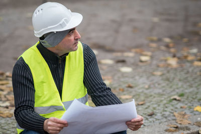 Architect holding blueprint working at construction site