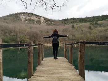 Rear view of woman walking on pier over lake