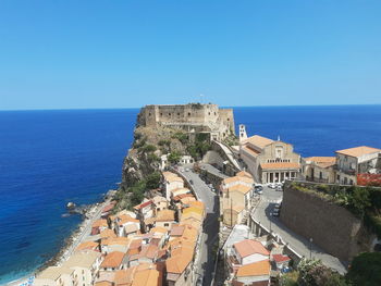 High angle view of buildings by sea against clear sky