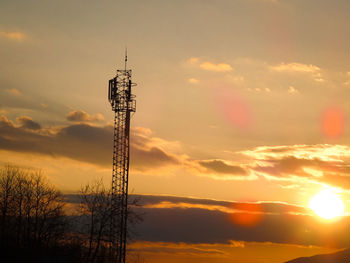 Low angle view of silhouette communications tower against sky during sunset