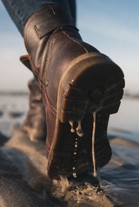 Low section of man wearing shoes on beach