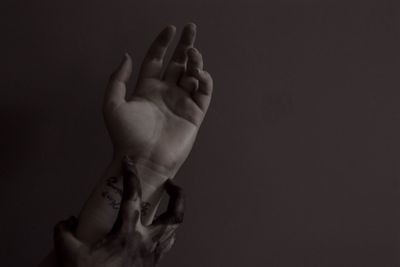 Cropped dirty hand holding tattooed person against gray background