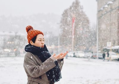 Woman standing in city during snowfall