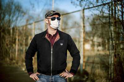 Portrait of young man in mask standing against sports field