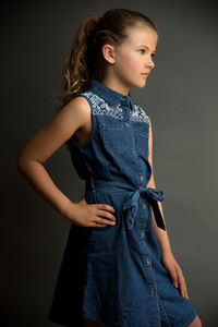 Side view of young woman standing against black background