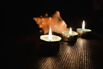 Close-up of lit candles on table at night