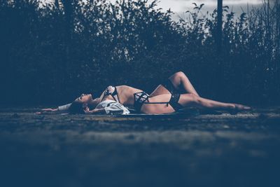 Side view of young woman in lingerie lying in park