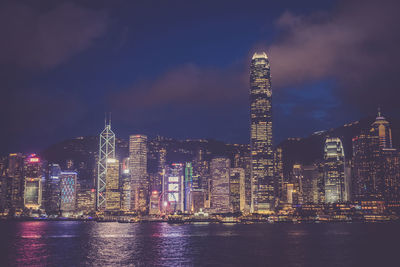 Illuminated modern buildings in city against sky at night