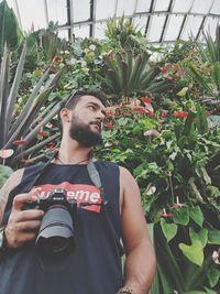 Young man standing by flowering plants