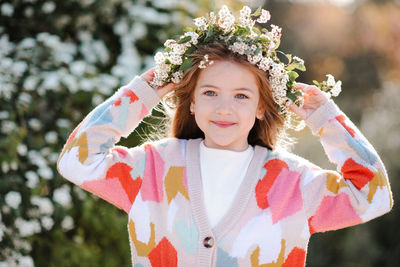 Happy smiling kid girl 6-7 year old wear knit colorful sweater wreath hairstyle with flowers