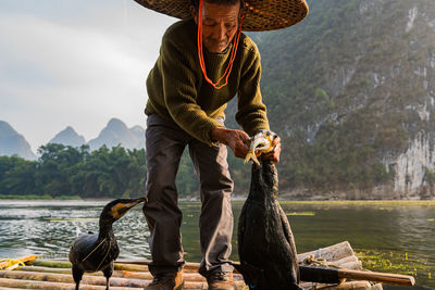 Man wearing hat standing on raft with bird