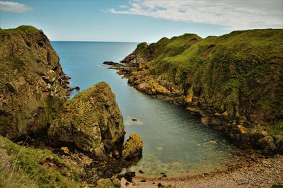 Scenic view of sea by cliff against sky