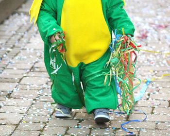 Low section of child in costume walking on footpath during carnival