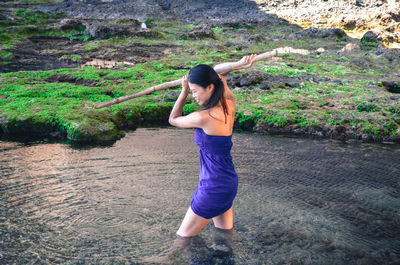 Full length portrait of young woman standing in water