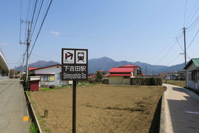 Road sign by city against clear sky