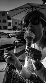 Woman wearing sunglasses eating ice cream in city