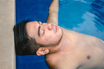 High angle view of shirtless man relaxing in swimming pool
