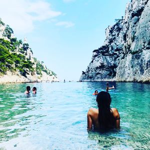 People swimming in sea against sky