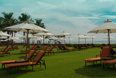 Empty chairs and tables on beach against sky