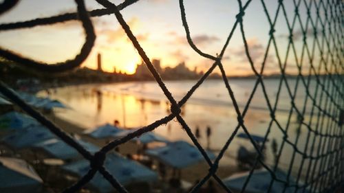 Beach seen through fence at sunset