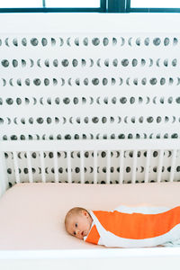 View from above of a newborn baby girl swaddled in a modern crib