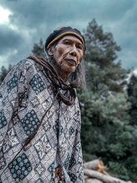 An old man with dreadlocks wearing a batik outfit.with a reggae hat.posing in front of the camera