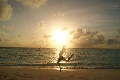 Silhouette man standing on beach against sky during sunset