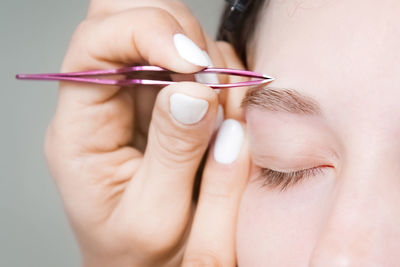 Makeup artist plucks the eyebrows of a woman without makeup with tweezers. beautiful eyebrows close