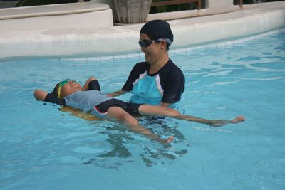 Mother swimming with son in pool