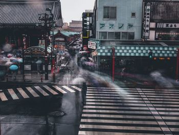 Wet road by buildings in city during rainy season