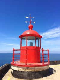 Lighthouse by sea against blue sky