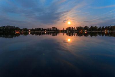 Trees reflecting in lake against sky during sunset