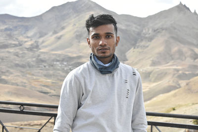 Portrait of young man standing against mountains