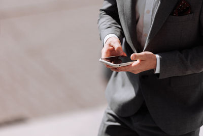 Midsection of businessman using mobile phone