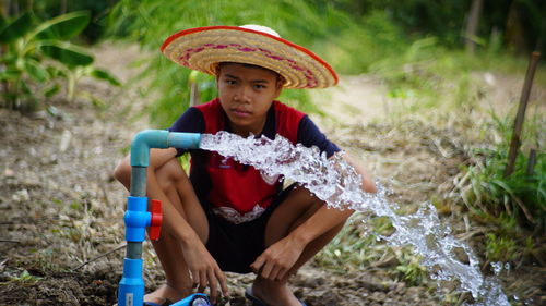 Portrait of boy sitting by water pipe