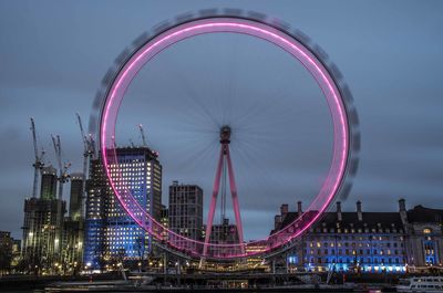 Ferris wheel in city against sky at night