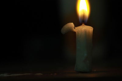 Close-up of lit candle on table in darkroom