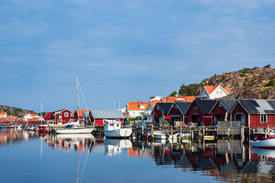 Boats moored at harbor by buildings against sky