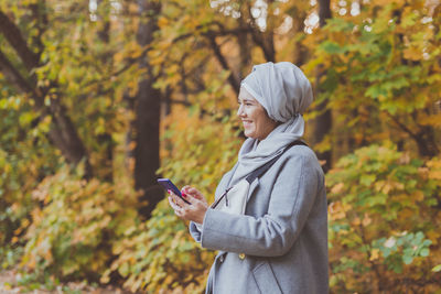 Full length of man using phone while standing on tree