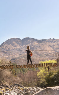 Rear view of man standing on mountain against clear sky