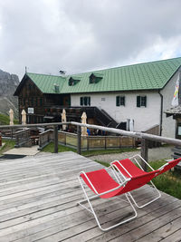 Chairs and tables outside house against sky