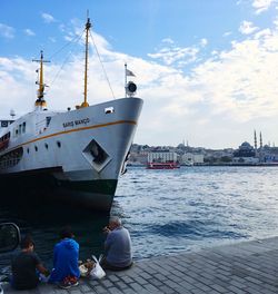 Rear view of people on harbor by sea against sky