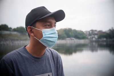Portrait of young man standing against lake