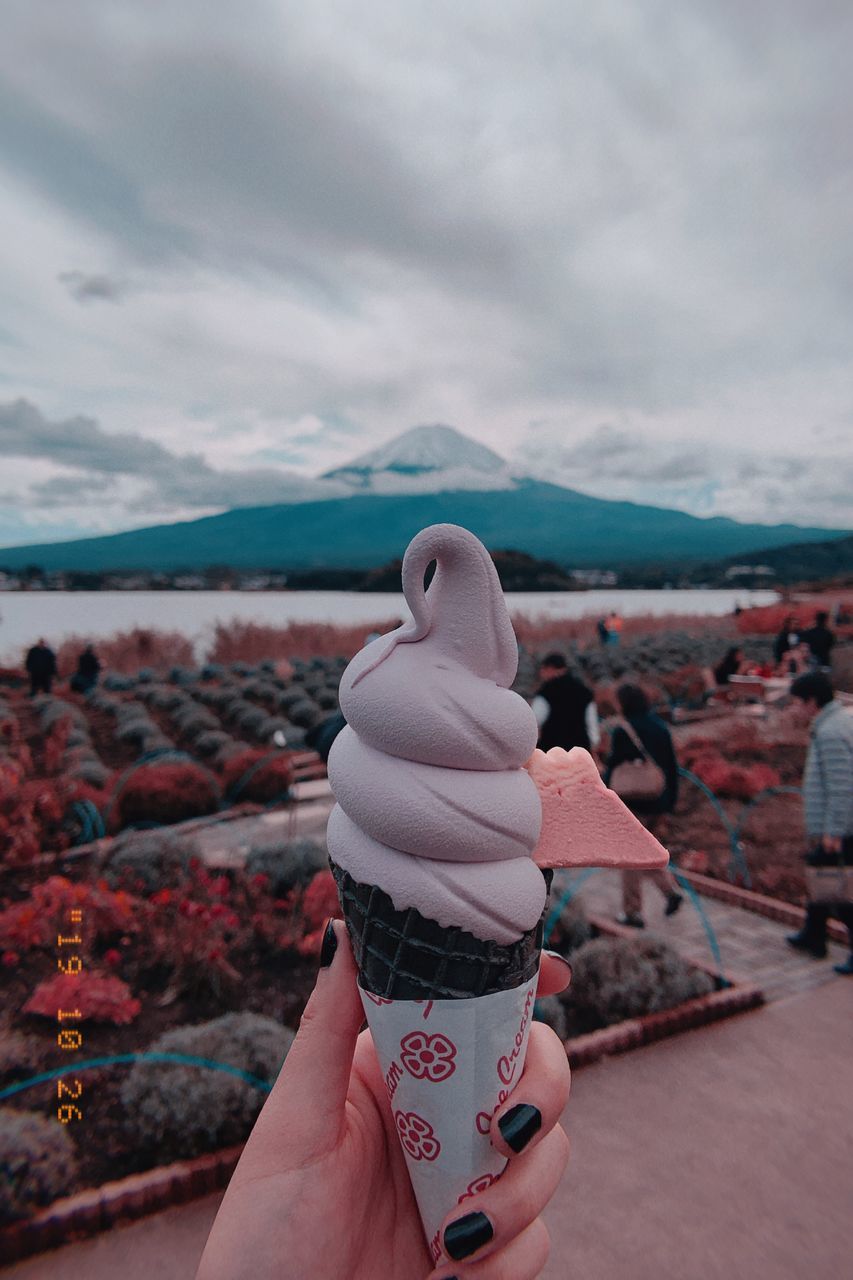 human hand, hand, one person, real people, personal perspective, human body part, holding, cloud - sky, unrecognizable person, sky, day, focus on foreground, lifestyles, body part, ice cream, frozen food, sweet food, nature, leisure activity, dairy product, finger, outdoors, temptation