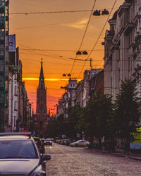 Street amidst buildings against sky during sunset