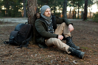 Young man sitting on tree trunk